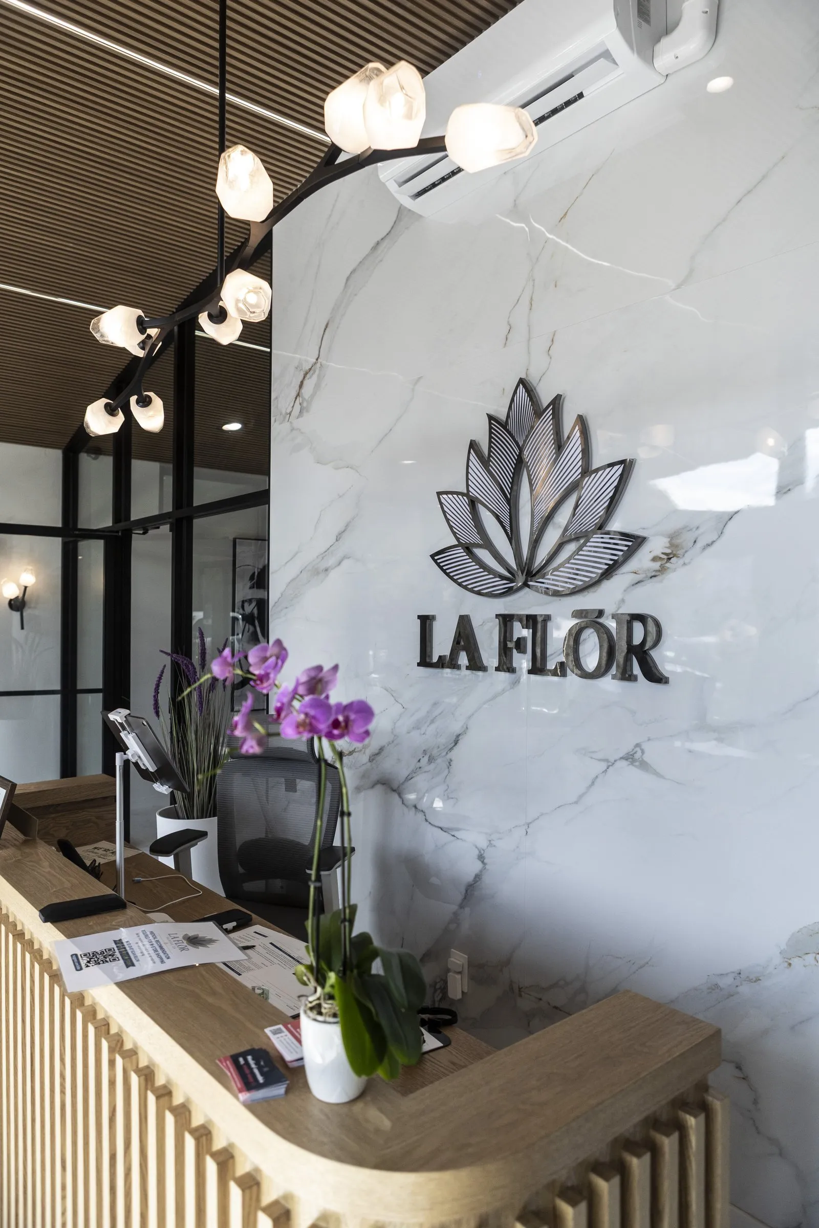 The La Flōr reception desk, the lotus logo on the marble wall behind it.
