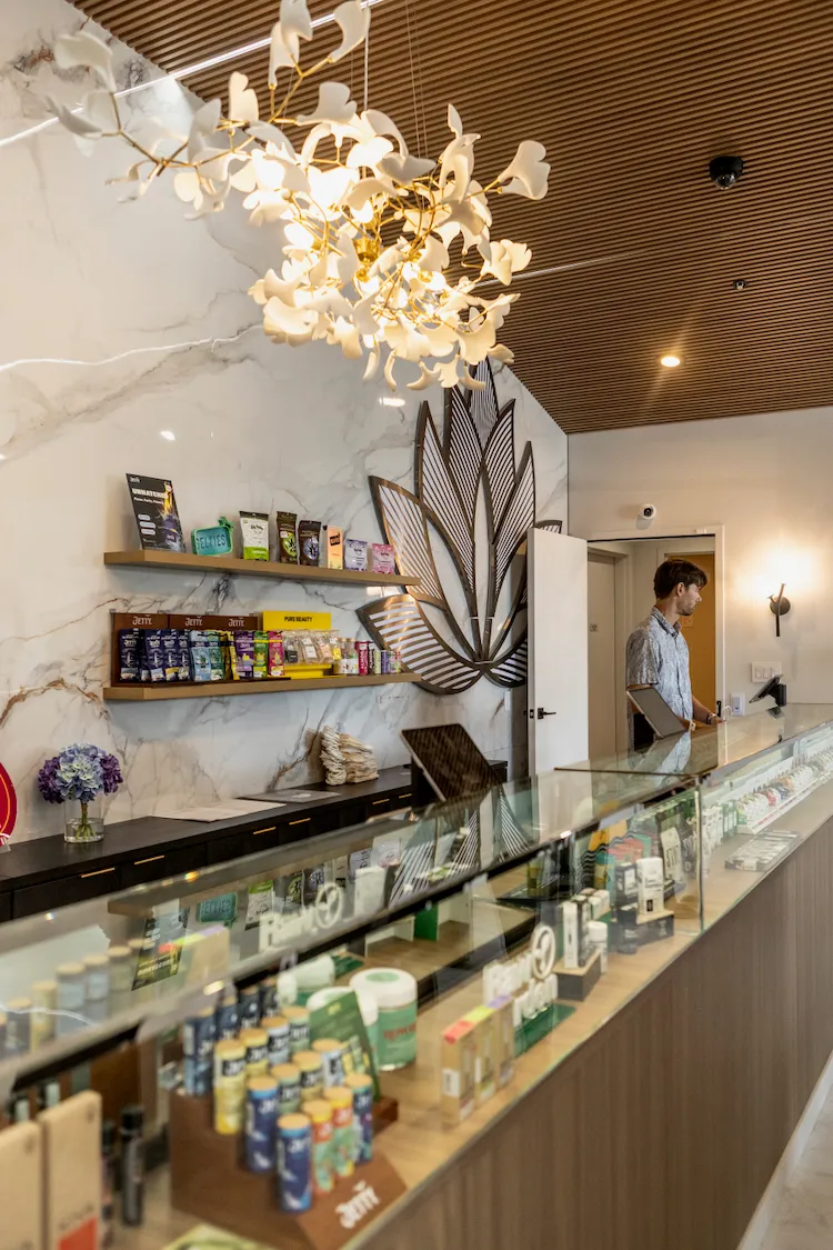 The La Flōr counter under the ginkgo-branch chandelier, with the metal lotus sculpture on the marble wall behind.