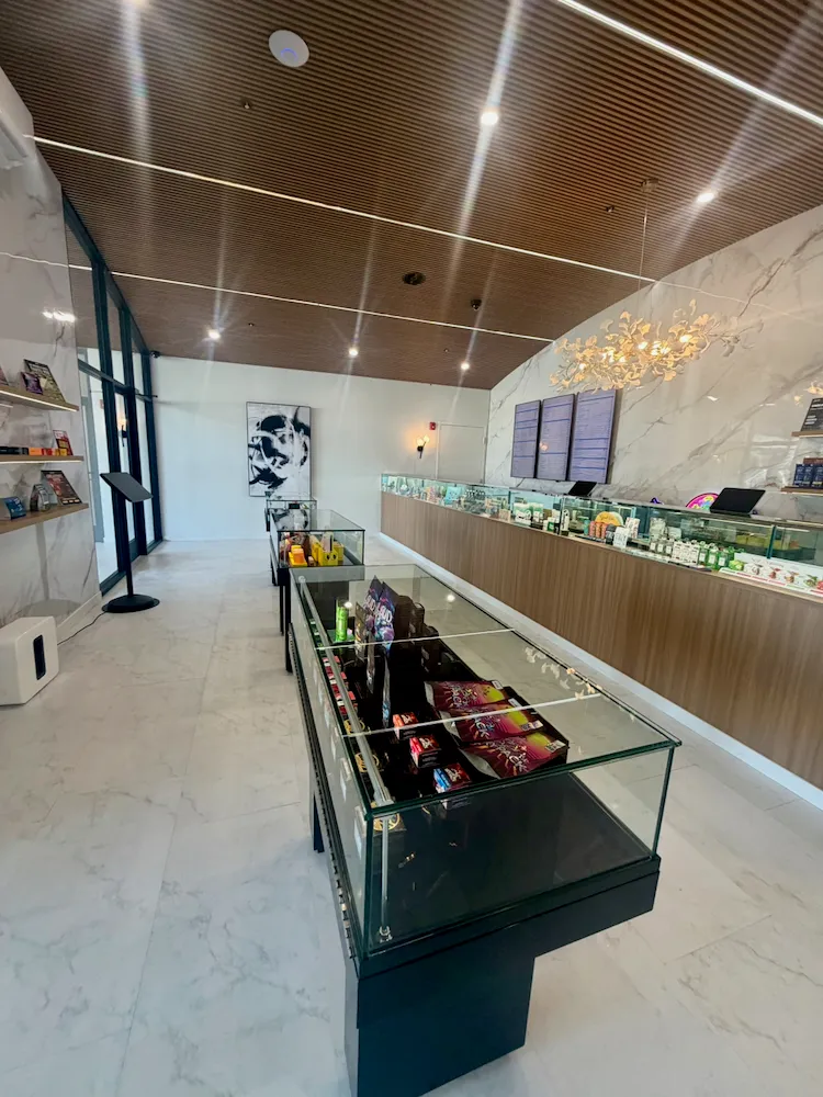 The La Flōr retail floor: lit display cases running the length of the marble-and-walnut room under the wood-slat ceiling.