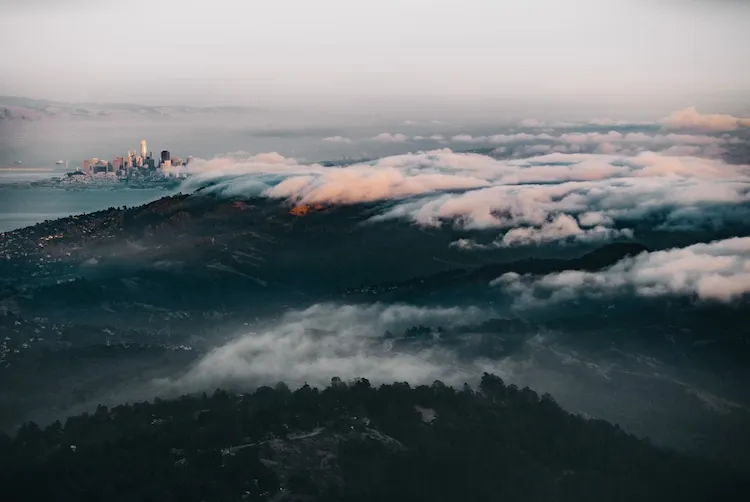 Fog pouring over the ridgeline of Mount Tamalpais at dusk, the hills of Marin below.