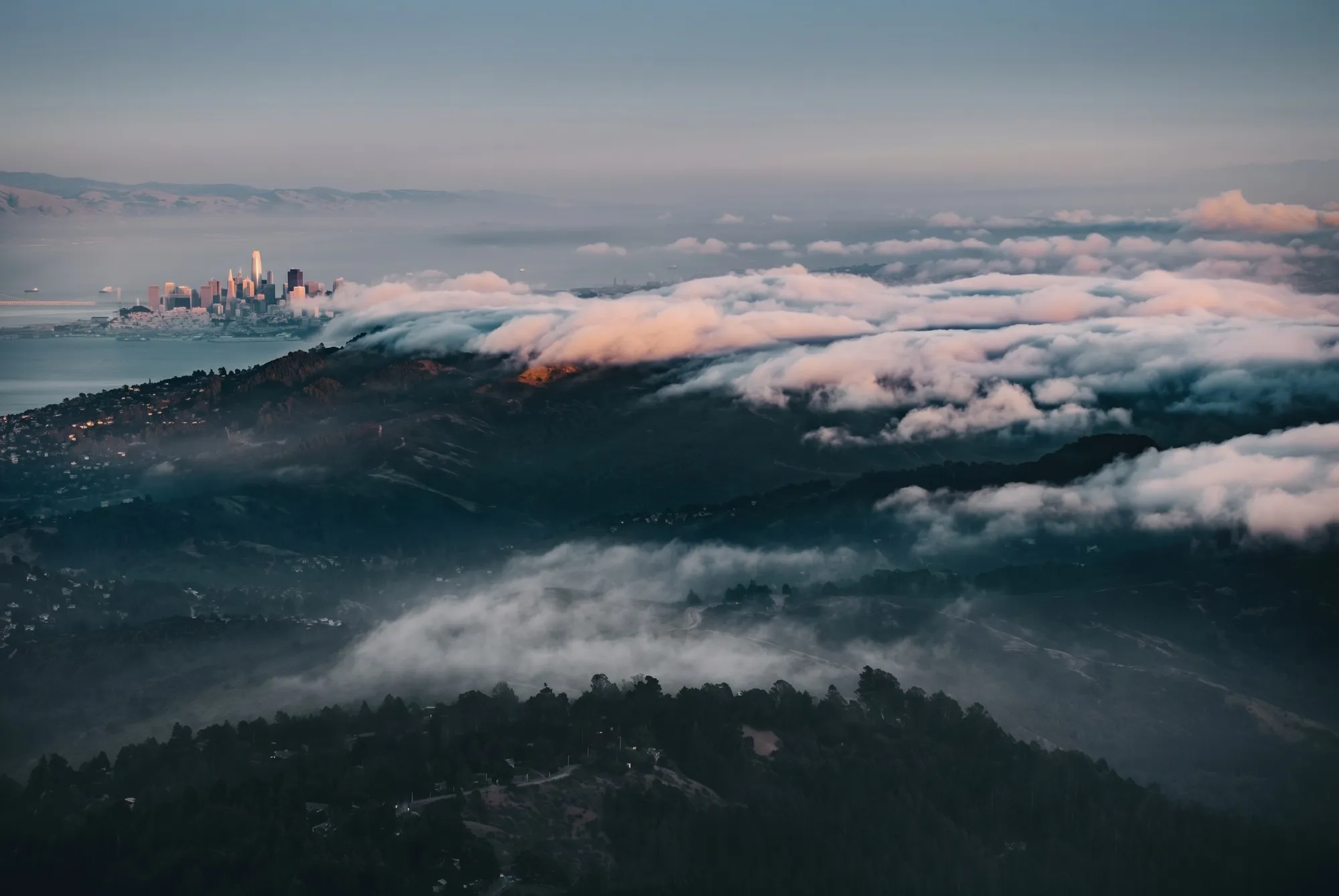 Fog pouring over the ridgeline of Mount Tamalpais at dusk, the hills of Marin below.