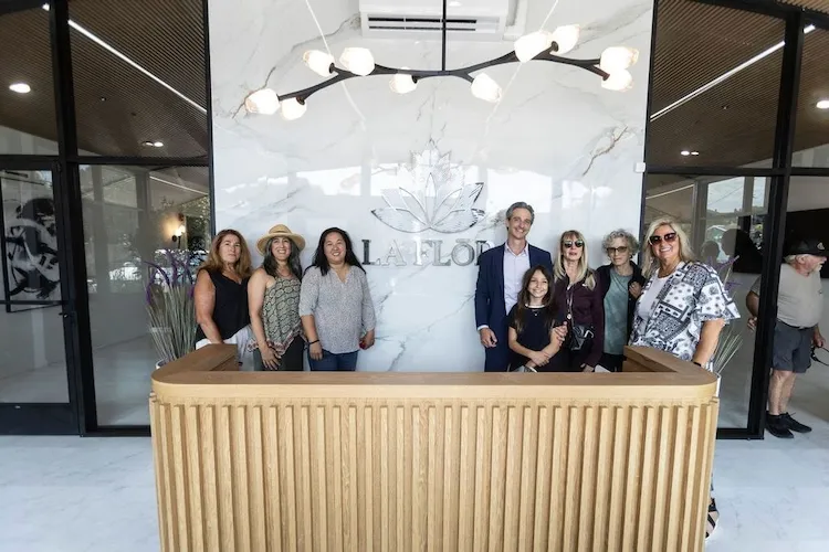 Neighbors and friends gathered at the La Flōr reception counter beneath the marble lotus wall on opening day.