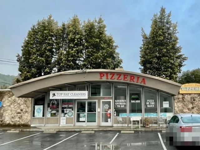 The 1601 Sir Francis Drake building before La Flōr, home to Mauro's Pasta Pizzeria and Top Hat Cleaners, on an overcast day.